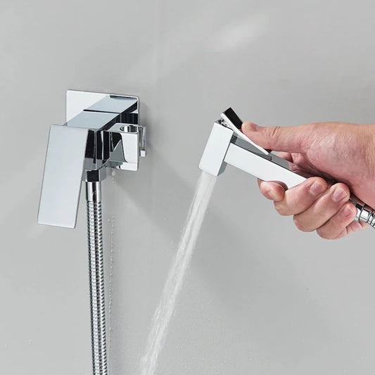 A hand holds the Valmont Wall-Mounted Toilet Sprayer by Morsale.com, with water flowing from its sleek brass nozzle against a light gray background.