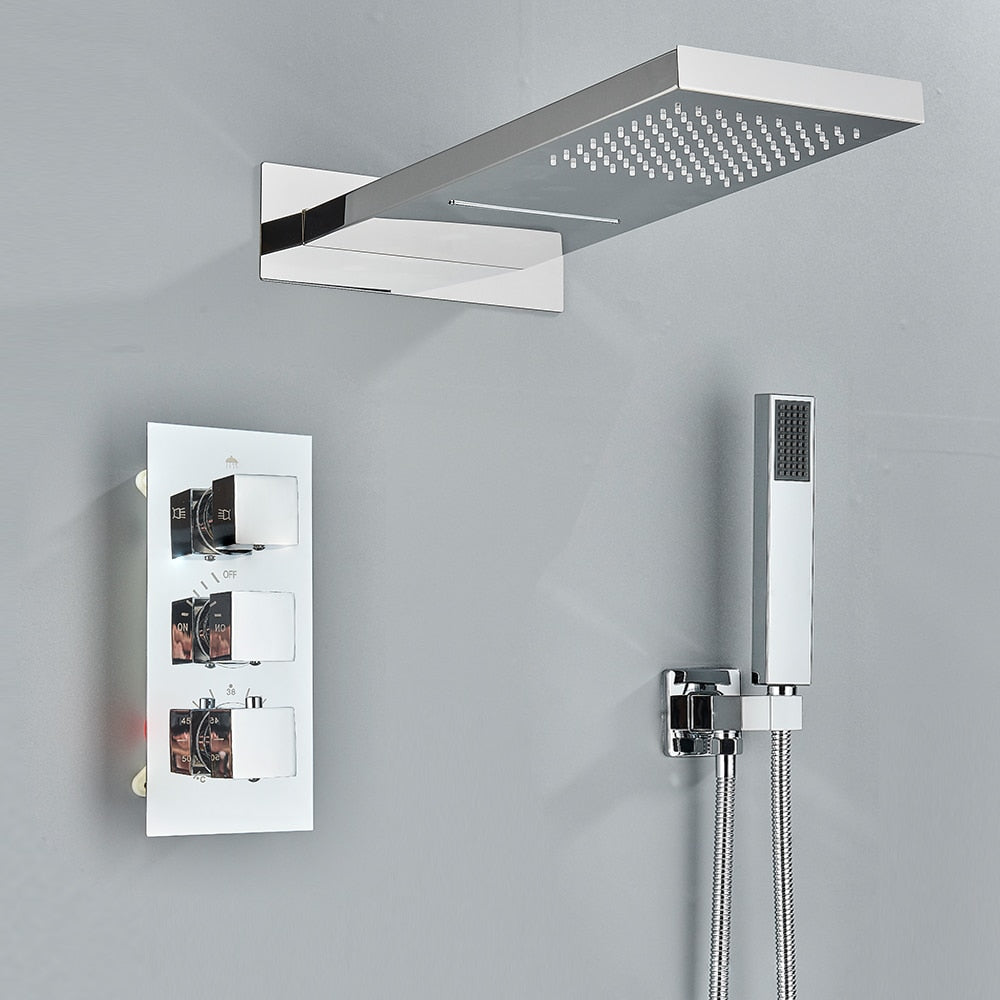 A minimalist shower setup is showcased by AllFixture's Thermostatic Wall Mounted Waterfall Rainfall Shower Head System, featuring a square, gold-toned overhead showerhead, three gold control knobs on a rectangular panel, and a matching handheld showerhead mounted on the wall. This sleek design with its gray background is complemented by an elegant AllFixture gold shower faucet.