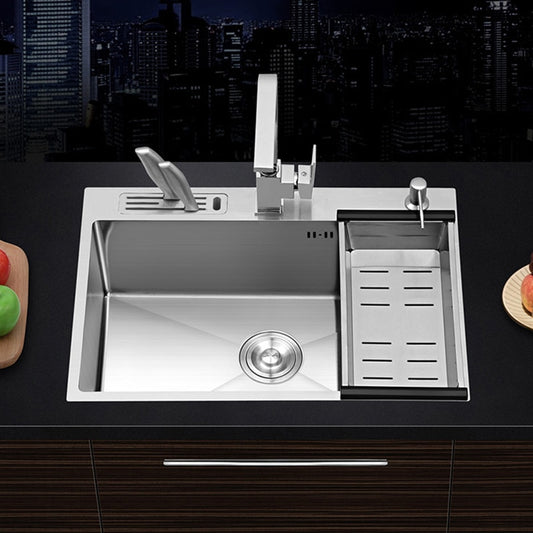 An AllFixture Stainless Steel Topmount Kitchen Sink With Knife Holder, featuring a built-in cutting board, a sleek kitchen faucet, and a sliding drain tray. The sink is set against a backdrop of a nighttime city skyline seen through a window, with apples and tomatoes on the nearby cutting board.