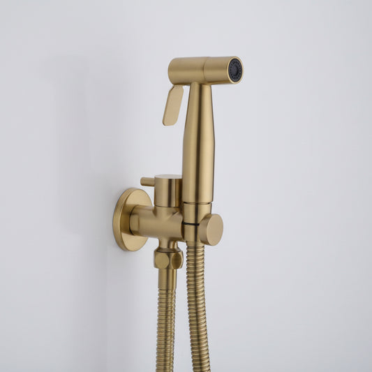 The AllFixture Wasser™ Solid Brass handheld Toilet Sprayer Faucet in gold includes a flexible hose and a wall-mounted holder, elegantly installed on a white wall.